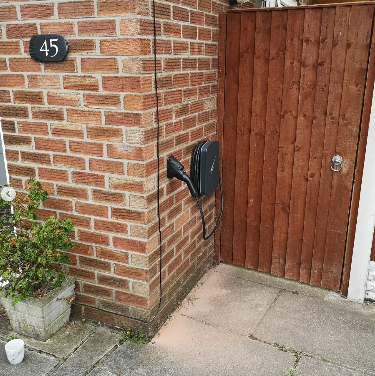 Tethered EV charger installed beside a side gate at a UK home