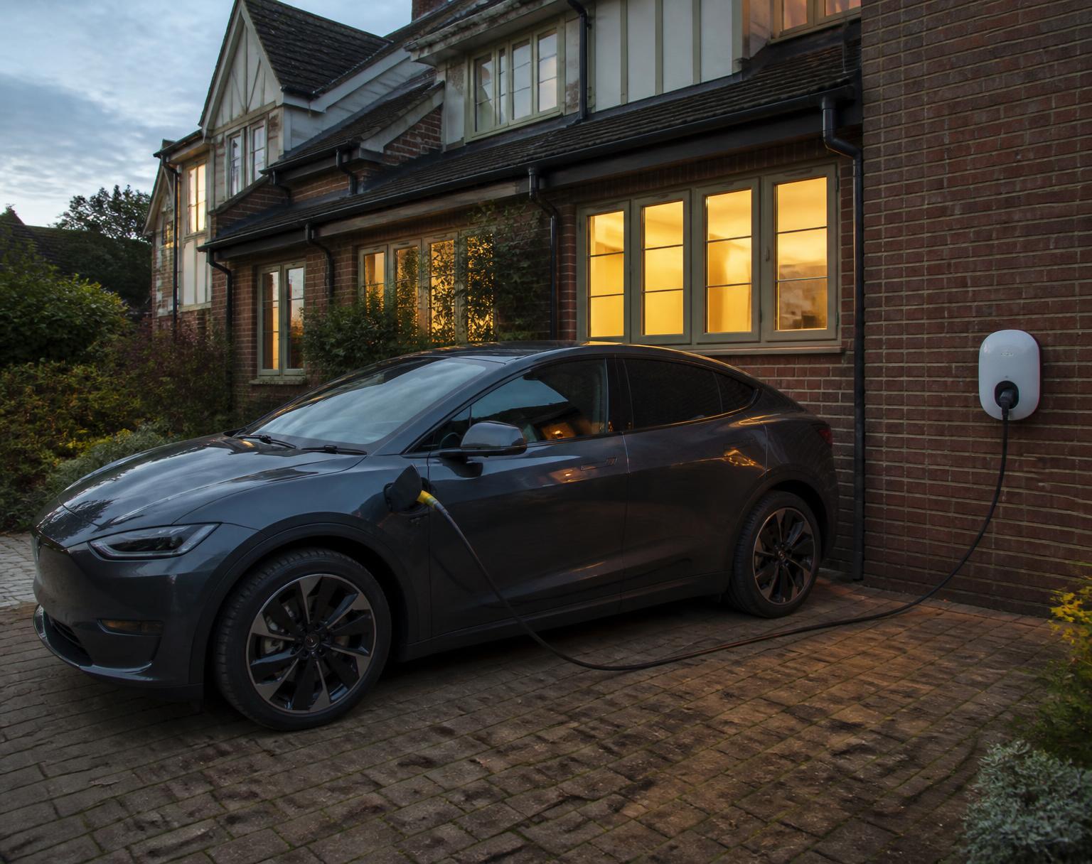 EV charger installed on a modern brick house with car on the driveway